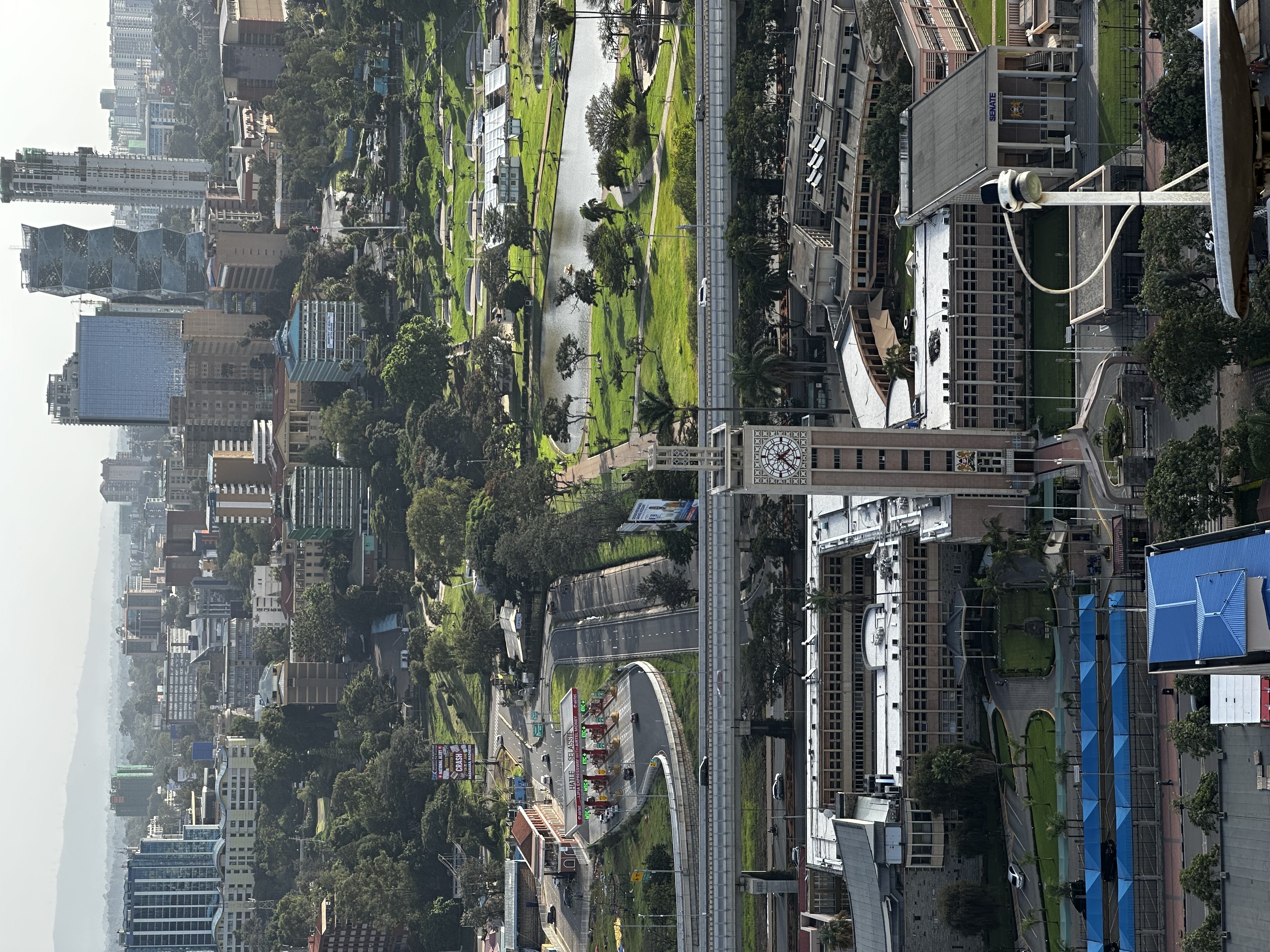 Urban skyline with clock tower, green park, and modern high-rise buildings.